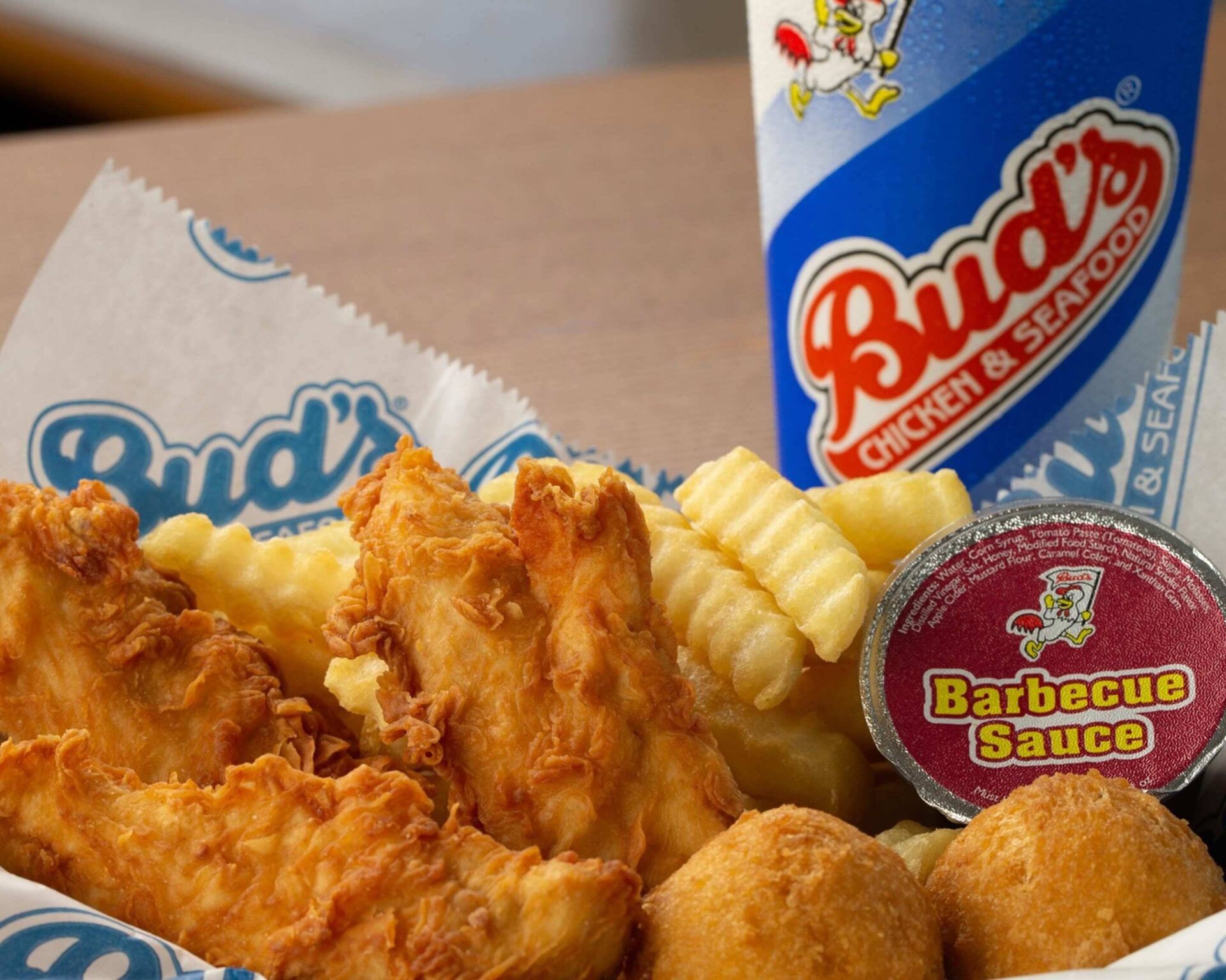 Bud’s Chicken & Seafood chicken tenders meal with crinkle-cut fries, hush puppies, and barbecue sauce
